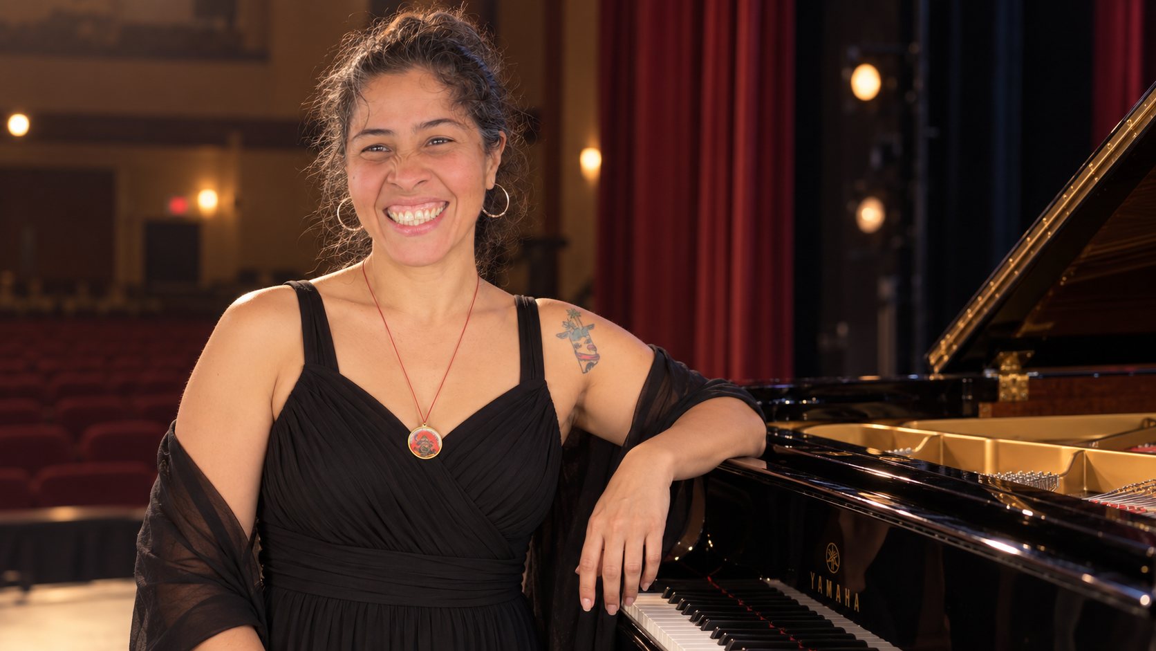 Mayda Cuellar Bustamante smiling beside a grand piano